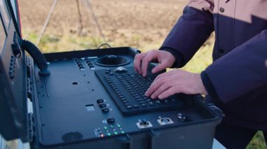 Bir pilot uzmanın elleri. Sahadaki bir kontrol üssünde uçan bir dron. İnsansız hava aracından gerçek zamanlı bilgi ve video alan yüksek performanslı bilgisayar