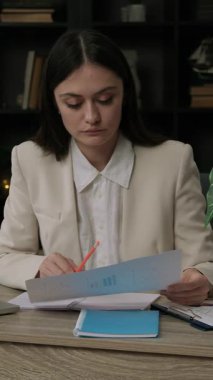 Kafası karışık ve ciddi kadın muhasebeci bilgisayardaki belgeleri ve masaları analiz eder ve kontrol eder. Klasik takım elbiseli genç bayan çalışanlar rakamlar ve verilerle dikkatli ve titiz bir şekilde çalışırlar.