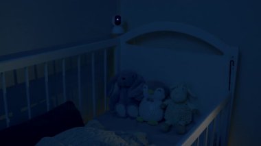 Beşikteki bebek uyuyor. Bebeği izleyen bebek beşiğinden sarkan güvenlik kamerası. Modern dijital cihaz, geceleri bebek beşiğini kablosuz ağ ile izliyor. Güvenlik ve güvenlik.