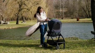 Genç anne bebeği bebek arabasında uyurken parkta bir kahvenin tadını çıkarıyor. Kadın doğum izninde bebeğiyle rüzgârda doğanın tadını çıkarıyor. Mutlu annelik