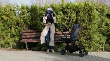 Genç ve güzel anne bebeğini parkta bir yürüyüş için bebek arabasına koyar. Parkta bir sandalyede oturan kadın bebeğini kucağına alır ve dışarıda temiz havada birlikte vakit geçirir.