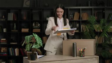 Heyecanlı genç bayan uzman ofis masasını düzenliyor ve yeni işyerindeki kişisel eşyalarını çıkarıyor. Klasik takım elbiseli esmer kadın, bilgisayarını masaya yerleştiriyor ve açıyor..