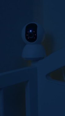 Bebek beşiğinden sarkan güvenlik kamerası geceleri uyurken bebeklerin uyumasını izliyor ve gözetliyor. Telefondaki uygulamayla kablosuz internet üzerinden dijital cihaz. Güvenlik ve güvenlik.