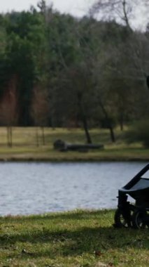 Güzel ve şık bir genç anne, doğada göletin yanındaki parkta bebek arabasında bebekle yürüyor. Kadın doğum iznini sever ve çocukla vakit geçirir. Mutlu annelik ve mutlu annelik