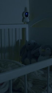 Güzel ve modern beşik ve bebek geceleri karyolada huzur içinde uyur. Bebeği izleyen bebek beşiğinden sarkan güvenlik kamerası. Wi-Fi üzerinden dijital aygıt. Güvenlik ve güvenlik.