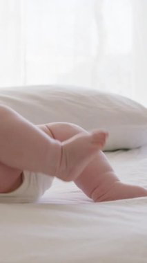 Tombul bebek masajdan sonra rahat ve hareketli yatakta uzanmış, kollarını ve bacaklarını sallıyor. Bilinmeyen beyaz elbiseli bebek, evinin sessiz vahasında yatağında sırt üstü yatıyor.