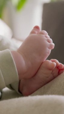 İlahi sabah ışığında çıplak ayaklı bir bebeğin yakın çekimi. Bebek annesinin kollarında yatıyor ve elleriyle ve ayaklarıyla sessizce oynuyor. Tombul yeni doğan annelerin sıcak ve sevgi dolu kollarından hoşlanır.