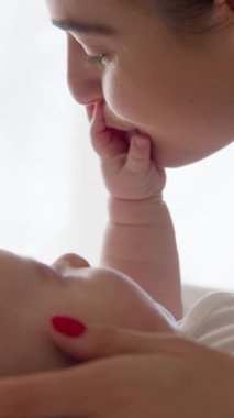 Şefkat ve anne sevgisi. Annesine sevgiyle bakan ve eliyle annesinin yüzüne dokunan bir bebeğin yakın plan portresi. Anne, kutsal sabah ışığında bebeklerin elini öpüyor.