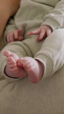 Kanepede bebek tutan bir kadının yakın plan görüntüsü. Sevgi dolu ve şefkatli bir anne, ufaklıkla oynuyor ve ona birlikte kaliteli zaman geçirtiyor. Bir bebeğin çıplak ve küçük ayakları.