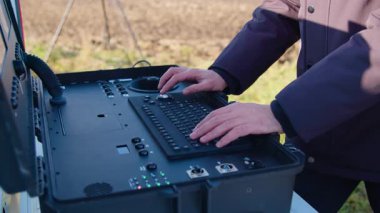 Bir erkek pilotu havada uçan bir drone 'a teslim eder. Teknoloji uzmanlarının yardımıyla devlet güvenliği. Polis uzun mesafelerden gerçek zamanlı görüntü aktarımı için akıllı bir kontrol paneli kullanıyor..