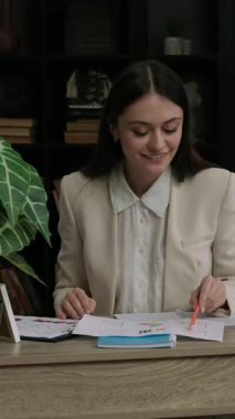 Profesyonel iş kadını mali belgelerdeki rakamları karşılaştırıyor. Solak kadın ofis çalışanı gülümsemesi kağıtlardaki tutarsızlıkları tanımlar.