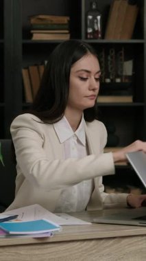 Genç iş kadını, görevleri yerine getirmek için gümüş dizüstü bilgisayar açıyor. Yoğunlaşmış kadın ofis çalışanı verimli bir iş gününe hazırlanıyor