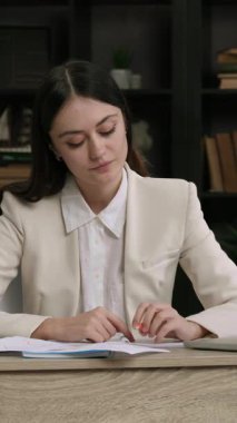 Rahat iş kadını, modern ofisteki işyerinde dinlenmek için zaman ayırıyor. Gülümseyen genç kadın tatil hakkında düşünüyor.