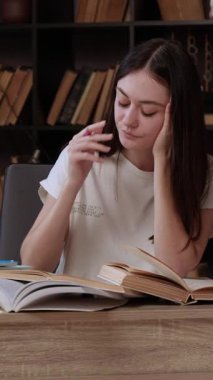 Kitaplardan, internetten ders çalışan ve notlar alan ciddi bir genç kadının portresi. Öğrenci, modern ve aydınlık bir odada, arkasında kitaplıklar olan bir proje hazırlıyor ve çalışıyor.