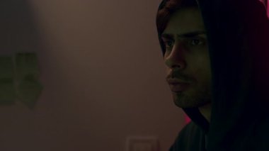 Kapüşonlu genç bir erkek bilgisayar korsanı para için yabancı hesapları ve sistemleri uzaktan hackliyor. Komutadaki tehlikeli bilgisayar korsanı sistemlere siber virüs bulaştırıyor.