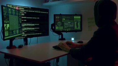 Büyük bilgisayar monitörlerinin önünde kafasında kapüşonu olan erkek hacker birkaç veri platformuna giriyor. Hackerlar tarafından veri sızıntıları ve gizli bilgiler.