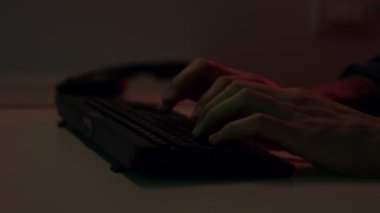 Tanınmayan bir hacker 'ın ellerini uzatıp dizüstü bilgisayarına klavye ve şifreleri kırmaya başlaması. Freelancer dizüstü bilgisayar kullanır ve klavyede daktilo ile evde çalışır