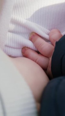 Anne göğsünden süt yiyen bebek görüntüsü. Dışarıda anne kucağında bir bebek emziriliyor. Anne, bebeğini kollarına alıp sevgiyle göğsüne bastırıyor.