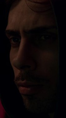 Kapüşonlu ciddi erkek hacker 'ın konsantre ve dikkatli bakışları bilgisayara bakıyor ve şifreleri ve bankacılık sistemlerini kırıyor. Komutadaki tehlikeli bilgisayar korsanı sistemlere siber virüs bulaştırıyor.