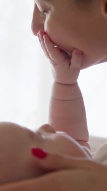 Annelik sevgisi kavramı. Bir bebeğin yakın plan portresi gülüyor ve annenle eğleniyor. Bebek anneye sevgiyle bakar ve annenin yüzüne eliyle dokunur. Anne elini öpüyor.