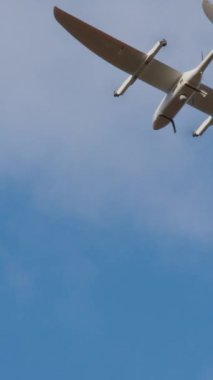 Uçak şeklinde beyaz akıllı dron uçar ve açık mavi gökyüzünde film çeker. Devlet güvenliği için en son model insansız hava aracı taramaları. Yenilikçi teknoloji kavramı