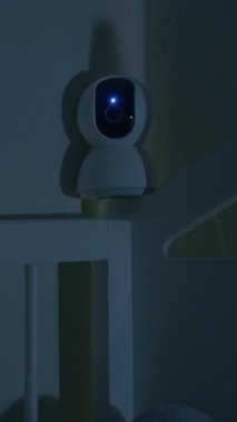 Bebek beşikten sarkan güvenlik kamerası o uyurken bebeği izliyor. Geceleri kablosuz ağ ile modern dijital cihaz bebek odasını ve beşiğini izliyor. Güvenlik ve güvenlik.