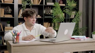 Genç adam evde sanal sınıfa aktif olarak katılıyor. Brunet, rahat ortamda dizüstü bilgisayarla ilgili dersler alıyor.