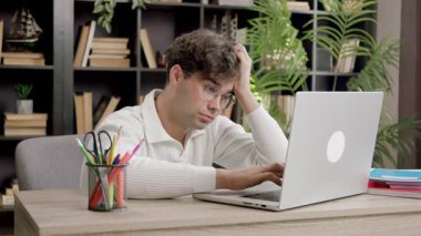 Adam kafaya dokunuyor ve masada çalışırken ekrana bakıyor. İnsan, zor bir günde dijital göreve yoğunlaşmayı ve içsel tepkiyi sürdürür