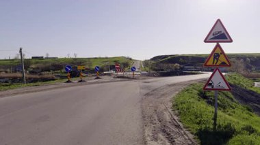 Trafik işaretleri, toprak kayması ve önümüzde inşaatla ilgili uyarıda bulunuyor. Boş viraj çitli tamir bölgesine götürür