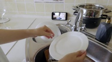 Ev hanımı bulaşıkları yıkıyor ve mutfaktaki akıllı telefondan dadı kamerası görüntülerini izliyor. Anne, yeni doğan bebeği evde angarya işleri yaparken kontrol ediyor.