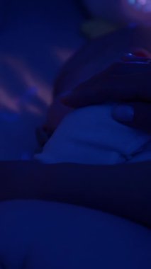 Anne, gece karyolasında huzur içinde uyuyabilmek için bebeğini içeri sokuyor. Anne ve bebek sıcak ve huzurlu bir atmosferde sevgi ve rahatlıkla