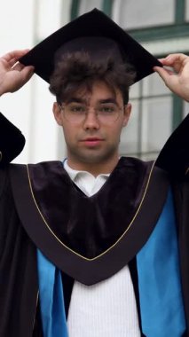 Genç adam akademik etkinliği kutlamadan önce havan topunu düzeltiyor. Adam üniversite binasının önünde başarıyı simgeliyor.