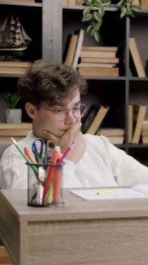 Tatmin olmamış adam çenesinin yanında el ele oturuyor ve kağıda bakıyor. Çalışma alanında hafif ışıklandırmayla düşünceli bir an başlıyor.