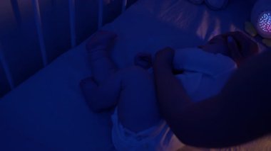 Sevgi dolu anne, geceleri bebek beşiğinde huzur içinde uyurken nazikçe dokunur. Huzurlu ve güvenli bir atmosferi olan huzurlu aile sahnesi