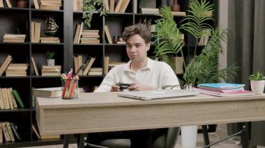 Ofis malzemeleri ve klasörlerle çevrili, elleri masa başında oyun oynayan bir adam. Rahatlamış atmosfer gelişigüzel aktiviteler gösteriyor.