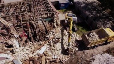 Kazıcı, eski evi yıkarken çöp kamyonuna enkaz yüklüyor. Etkin inşaat alanının yıkım ve yenilenme anı