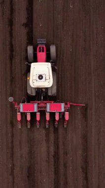 Modern traktör, dinamik tarım manzarasını gösteren tohumları geniş araziye eker. Parlak senset ışığı altında canlı çiftçilik faaliyetleri