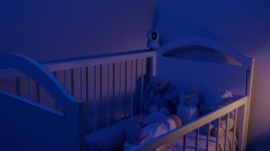 Sevimli pelüş bebekler izleme altında rahat bir beşikte uyur. Bebek, gece evdeki güvenlik kamerası kontrolüyle güvende.