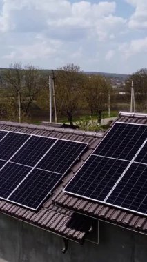 Koyu güneş panelleri, binanın çatısının kiremitli bölümlerine belirgin bir şekilde yerleştirilmiş. Bulutlu gökyüzünün altında ticari yenilenebilir enerji kurulumu