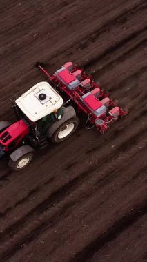 Kırmızı traktör, ekili tarlalarda verimli toprağı sürüp ekime hazırlanıyor. Çiftçilik teknikleri sahada aktif çalışmayı vurguluyor