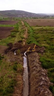 Traktör, ekiciyi yeni sürülmüş büyük kahverengi araziye çeker. Makine aktif ekimi gösteren toprak üzerinde belirgin düz çizgiler bırakır