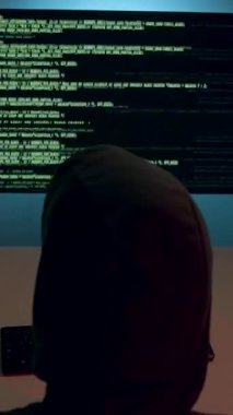 Karanlık bir odada siber bir suçlu yüksek güvenlikli ağları hacklemek için birden fazla ekranda çalışır. Veri ihlali ve çevrimiçi güvenlik tehdidi kavramı.