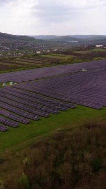 Güneş paneli çiftliği, gökyüzüne bakan panellerle yavaşça yuvarlanan yeşil arazi boyunca uzanır. Tepede yenilenebilir enerji kurulumu