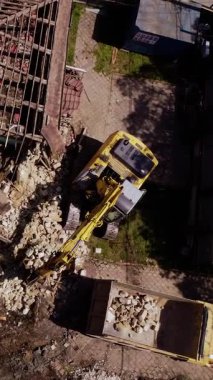 Çatı kazıcı tarafından temizlenirken kısmen yıkılmış bir bina. Etrafa saçılmış enkaz ve geniş çaplı yapısal hasar.