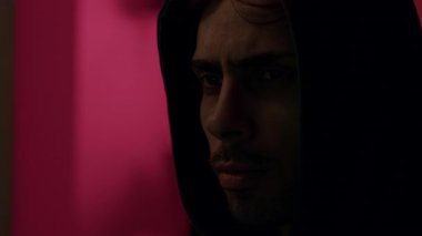 Kapüşonlu ciddi erkek hacker 'ın konsantre ve dikkatli bakışları bilgisayara bakıyor ve şifreleri ve bankacılık sistemlerini kırıyor. Komutadaki tehlikeli bilgisayar korsanı sistemlere siber virüs bulaştırıyor.