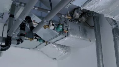 Endüstriyel elementlerle çağdaş bir ortamda hava dolaşımının ve verimliliğinin vurgulandığı, boru ve kanalların yer aldığı bir havalandırma sisteminin ayrıntılı görünümü