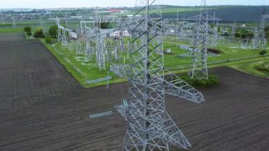 Yüksek voltajlı elektrik hatları ve iletim kuleleri, elektrik altyapısının ölçeği ve önemini vurgulayan yeşil bir alanda belirgin bir şekilde gösteriliyor.