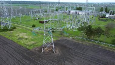Yüksek voltajlı iletim kuleleri ve elektrik hatları, ulusal elektrik şebekeleri ve enerji dağıtımının temel altyapısını gösteren geniş yeşil araziye hakim durumda