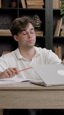 Adam dizüstü bilgisayarı kapatıyor ve masasında renkli kalemle kalem kırıyor. Erkek vücudu, tarafsız bir yüz ve uzak bir bakışla hareketsiz kalır.