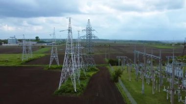 Enerji dağıtımı için gerekli altyapıyı gösteren elektrik hatları ve alt istasyonlarla çevrili uzun elektrik nakil kuleleri manzaraya hakim.